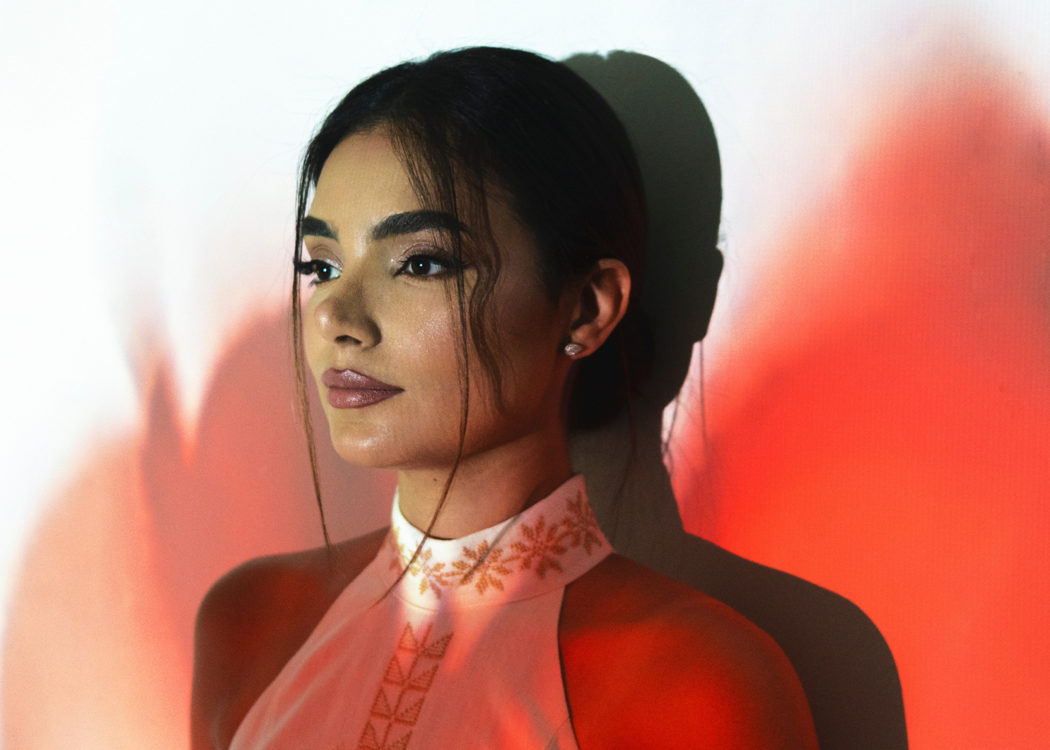 reema dahbour wearing a traditional outfit with intricate patterns against a red and white background