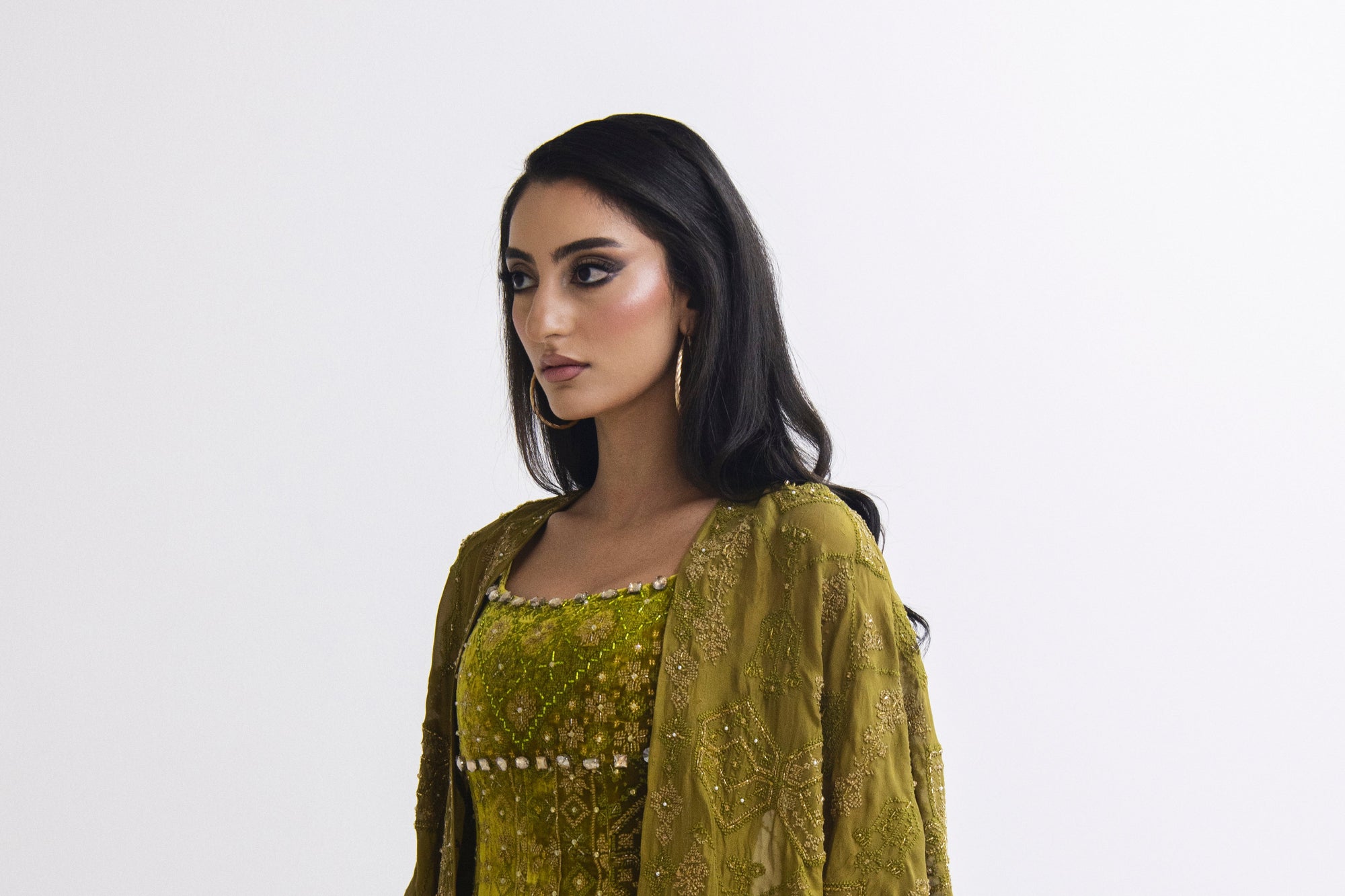 Woman wearing a green dress with a matching jacket on a white background